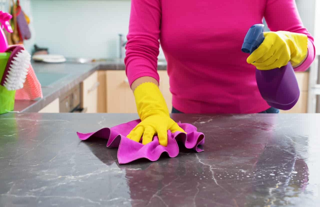 Woman cleaning a granite countertop.