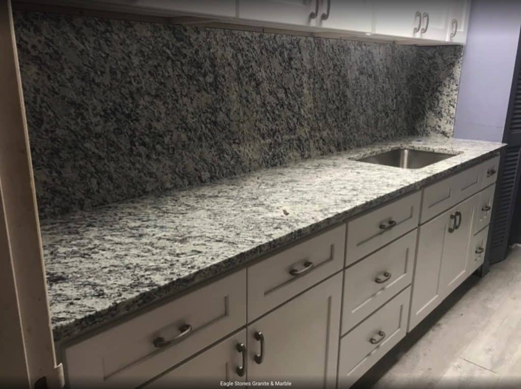White tones granite countertop with white cabinets and a sink